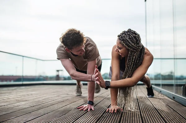 Молодая пара делает упражнения на открытом воздухе на террасе, спорт и здоровый образ жизни. — стоковое фото