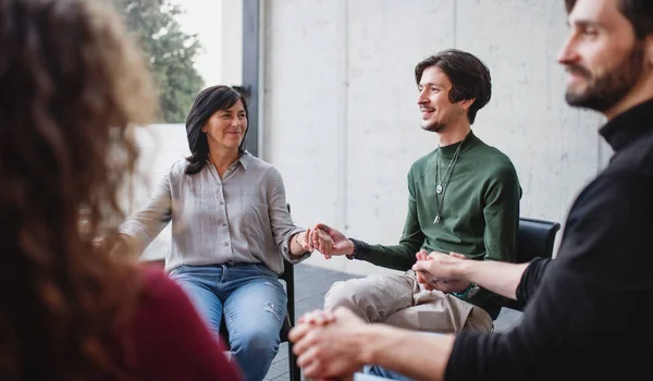 Men and women sitting in circle during group therapy, holding hands. — Stock Photo, Image