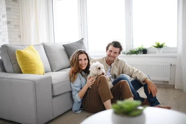 Glada unga par förälskade i hunden sitter inomhus, tittar på kameran. — Stockfoto