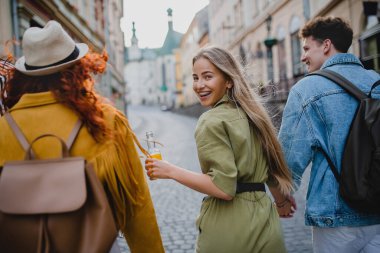 Kasabaya geziye gelen, yürüyen ve geriye bakan bir grup mutlu genç insan..