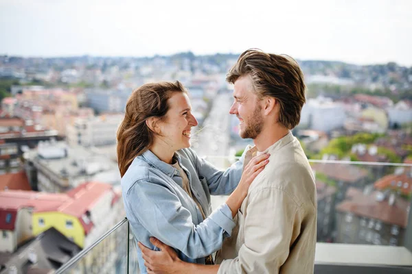 Happy young couple in love standing outdoors on balcony at home, looking at each other. — Stock Photo, Image
