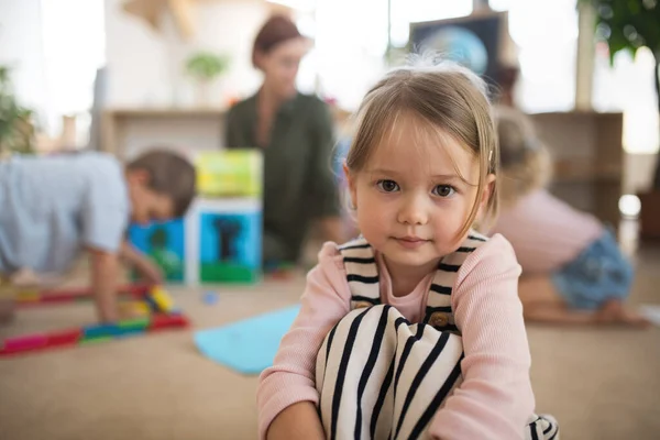 Portret małej przedszkolanki w pomieszczeniu szkolnym, patrzącej w kamerę. — Zdjęcie stockowe