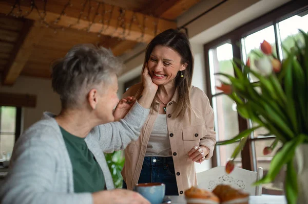 Feliz madre mayor tomando el té con la hija adulta en casa, hablando. — Foto de Stock