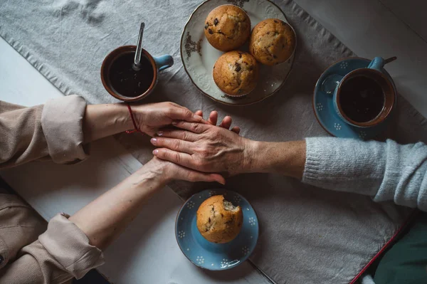 Ansicht von oben, wie eine Mutter mit ihrer erwachsenen Tochter zu Hause Kaffee trinkt und Händchen hält. — Stockfoto