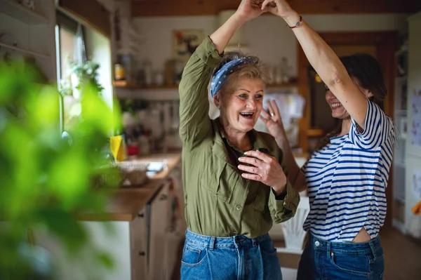 Happy senior mother having fun with adult daughter indoors at home, dancing. — Stock Photo, Image
