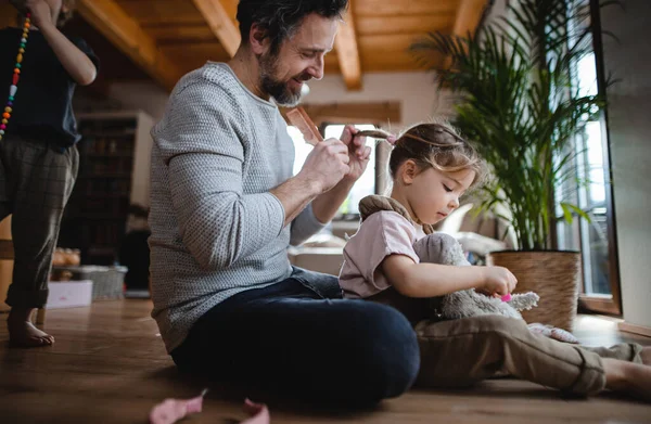 Maduro padre con pequeño hijo e hija descansando en casa, jugando y peinando el pelo. — Foto de Stock