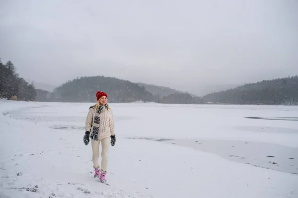 Actieve oudere vrouw op wandeling buiten in de besneeuwde natuur, wandelen door bevroren meer. — Stockfoto