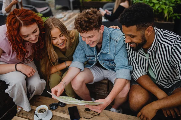 Vista superior do grupo de jovens felizes sentados no café ao ar livre na viagem à cidade, usando o mapa. — Fotografia de Stock