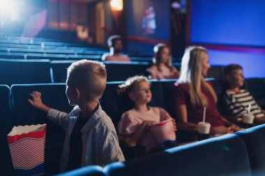 Anne ve küçük çocukları sinemada film izliyorlar..