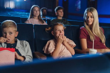 Anne ve küçük çocukları sinemada film izliyorlar..