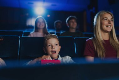 Anne ve küçük çocukları sinemada film izliyorlar..