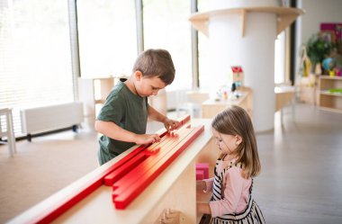 Bir grup küçük anaokulu öğrencisi sınıflarda oyun oynuyor, montessori öğrenimi.