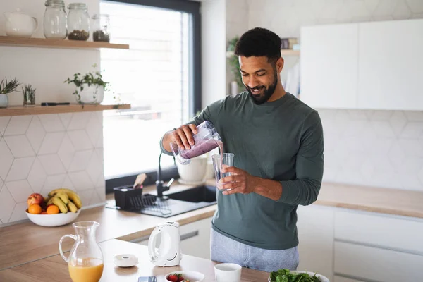 A fiatalember egészséges reggelit készít otthon, tejet öntve az üvegbe.. — Stock Fotó