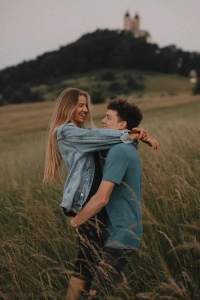 Jong stel op een wandeling in de natuur bij zonsondergang op het platteland, knuffelen. — Stockfoto