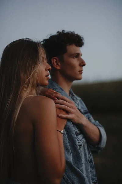 Jong stel op een wandeling in de natuur bij zonsondergang op het platteland, staande. — Stockfoto