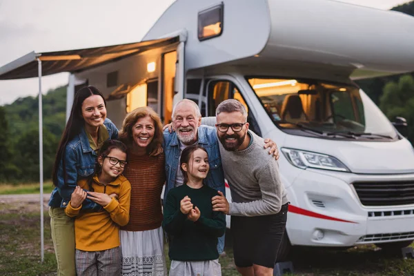 Multi-generation family looking at camera outdoors at dusk, caravan holiday trip. — Stock Photo, Image
