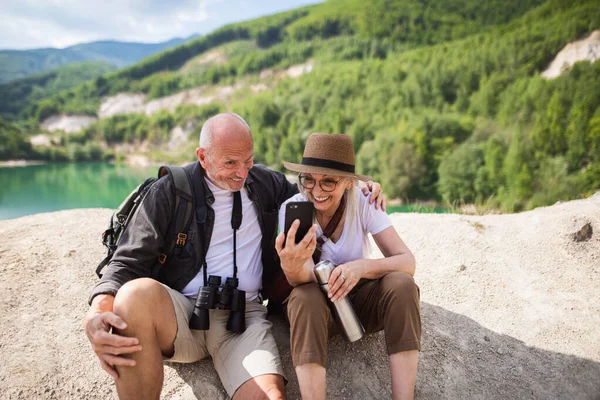 Feliz pareja mayor en viaje de senderismo en vacaciones de verano, haciendo caras al tomar selfie. —  Fotos de Stock