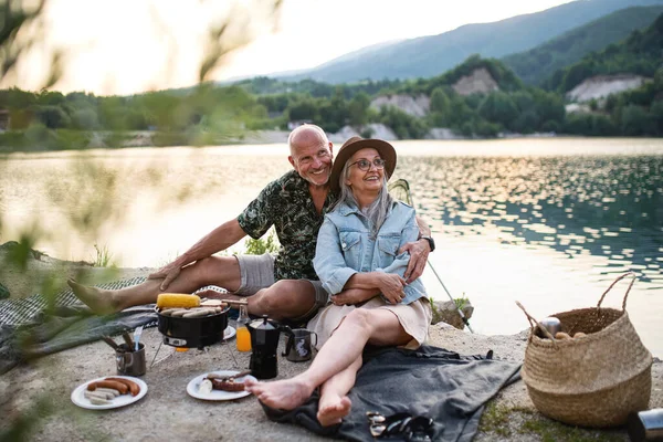 Szczęśliwa para seniorów odpoczywających na wakacyjnej wycieczce, grill nad jeziorem. — Zdjęcie stockowe