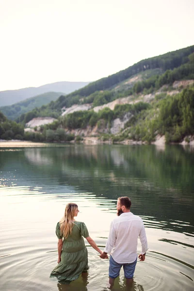 Achteraanzicht van volwassen paar in liefde staan in de natuur, hand in hand. — Stockfoto