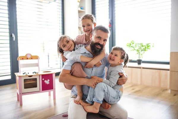 Père avec trois filles à l'intérieur à la maison, regardant la caméra. — Photo