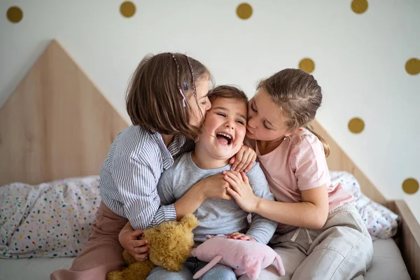 Portrait de trois filles sœurs à l'intérieur à la maison, embrasser. — Photo