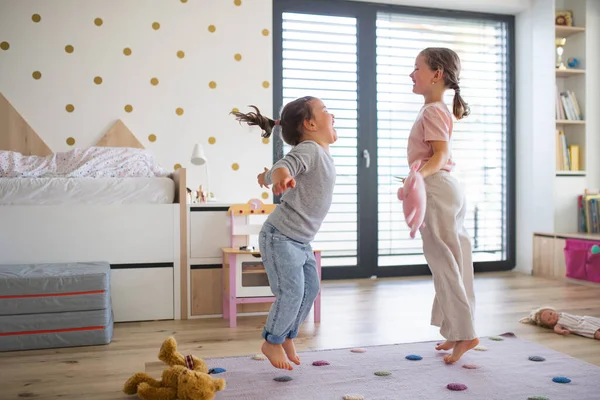 Retrato de meninas irmãs brincando dentro de casa, pulando. — Fotografia de Stock