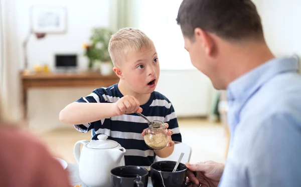 Boldog család Down-szindrómás fiúval az asztalnál, reggeliznek. — Stock Fotó