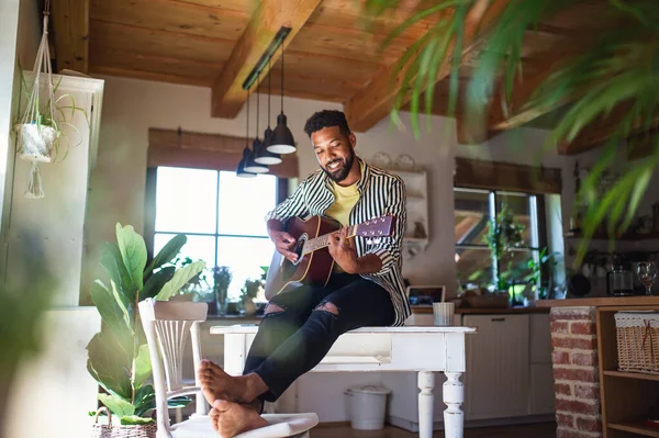 Счастливый молодой человек с гитарой внутри дома, расслабляющий. — стоковое фото