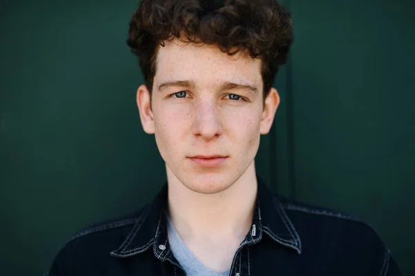 Close-up portrait of young man against green background outdoors, looking at camera. — Stock Photo, Image