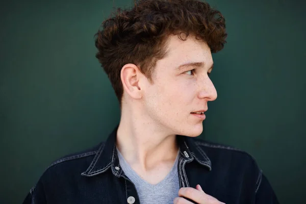 Close-up portrait of young man against green background outdoors. — Stock Photo, Image