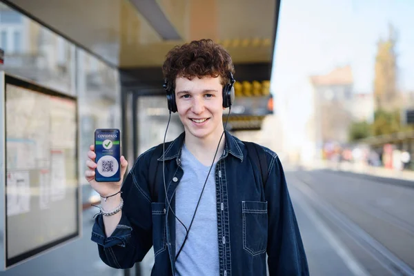 Ritratto di giovane pendolare in piedi all'aperto in città, mostrando covid pass su smartphone. — Foto Stock