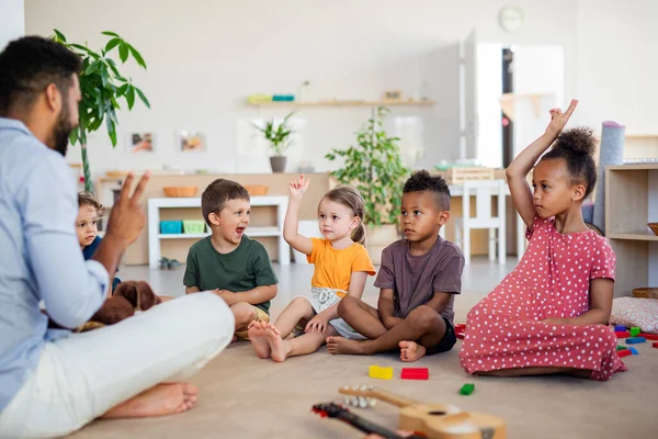 Gruppo di piccoli bambini della scuola materna seduti al piano interno in classe. — Foto Stock