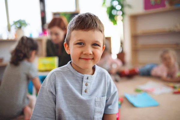 Portret małego przedszkolaka w salach lekcyjnych, patrzącego w kamerę. — Zdjęcie stockowe