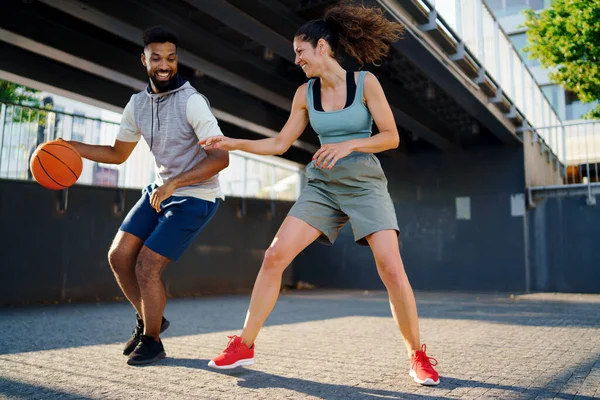 Férfi és nő barátok kosárlabdáznak a szabadban a városban. — Stock Fotó