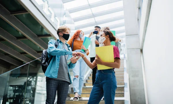 Üniversite öğrencileri merdivenlerden iniyor ve kapalı alanda karşılıyorlar, koronavirüs konsepti. — Stok fotoğraf