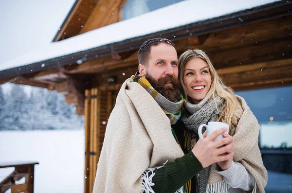 Porträtt av glada mogna par i kärlek njuter av semester i fjällstuga, står utomhus. — Stockfoto