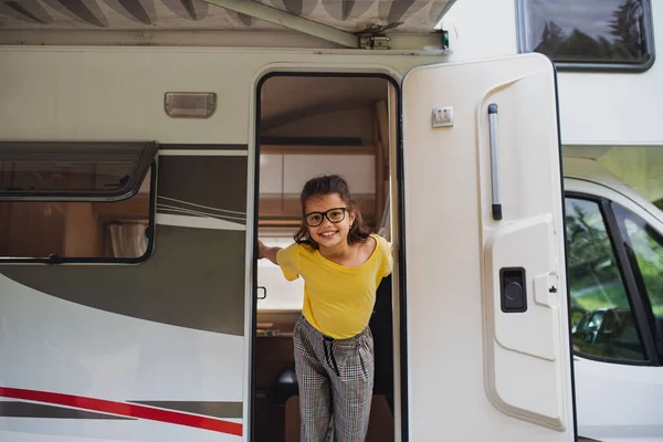 Menina pequena feliz em pé à porta da caravana, olhando para a câmera. Viagem de férias em família. — Fotografia de Stock