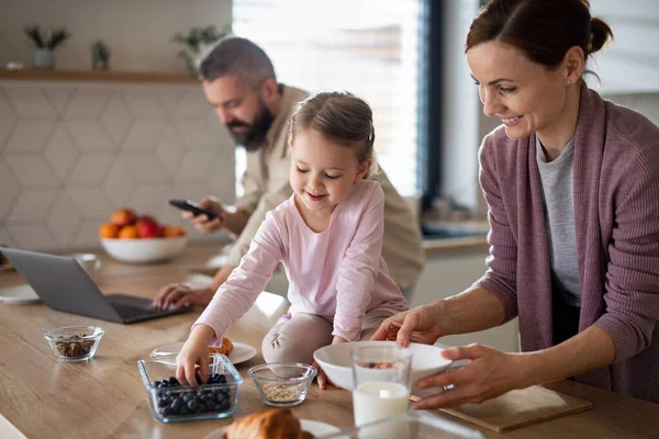 Famille avec petite fille à l'intérieur dans la cuisine à la maison, la vie quotidienne et le bureau à domicile avec concept enfant. — Photo