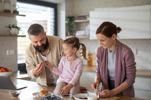 Family with small daughter indoors in kitchen at home, everyday life and home office with child concept. — Stock Photo, Image