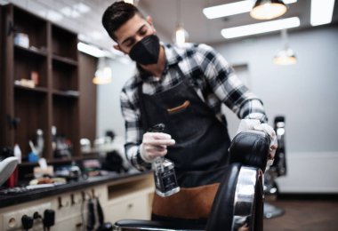 Genç adam berber dükkanında dezenfektan, koronavirüs ve yeni normal konsept..