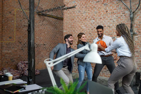 Gruppe gut gelaunter junger Geschäftsleute spielt im Büro Basketball und legt eine Pause ein. — Stockfoto