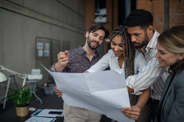 Jeunes gens d'affaires joyeux debout et travaillant dans le bureau, concept de coopération. — Photo