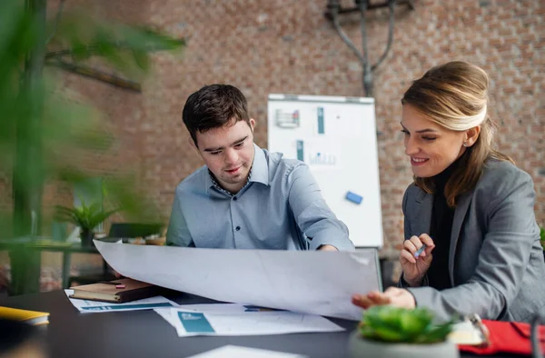 Happy down syndrome man with businesswoman colleague working in office, social inclusion and cooperation concept. — Stock Photo, Image