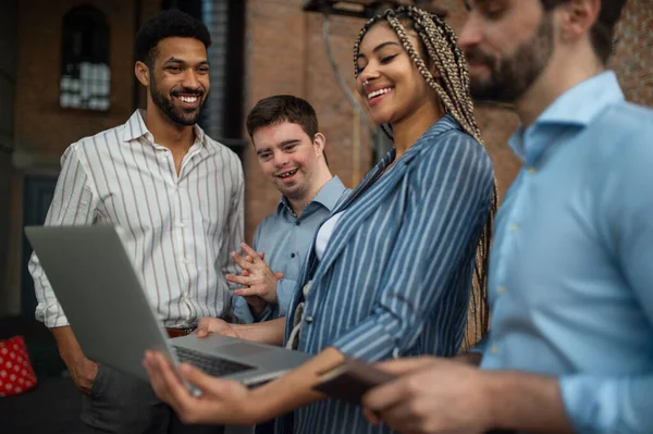 Vrolijke jonge ondernemers met laptop aan het werk, concept van sociale integratie en samenwerking. — Stockfoto