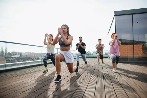 Grupa młodych ludzi ćwiczy na świeżym powietrzu na tarasie, sport i koncepcja zdrowego stylu życia. — Zdjęcie stockowe