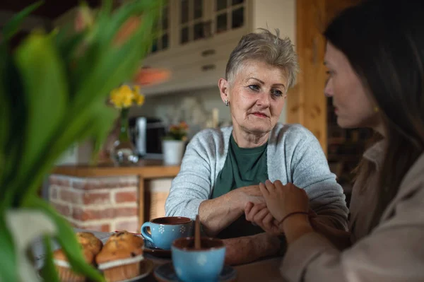 Sorglig äldre mor att dricka te med vuxen dotter inomhus, prata. — Stockfoto