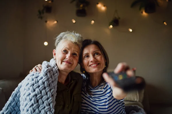 Porträt einer glücklichen Seniorin mit erwachsener Tochter zu Hause vor dem Fernseher. — Stockfoto