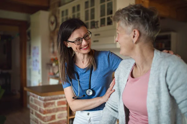 Hälso- och sjukvårdspersonal eller vårdgivare besöker äldre kvinna inomhus, stödjer. — Stockfoto