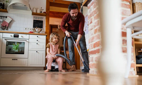 Padre con una pequeña hija revoloteando en el interior de casa, concepto de tareas diarias. — Foto de Stock