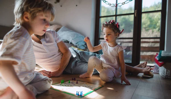 Onherkenbare vader met twee kleine kinderen die binnen rusten, bordspel spelen. — Stockfoto